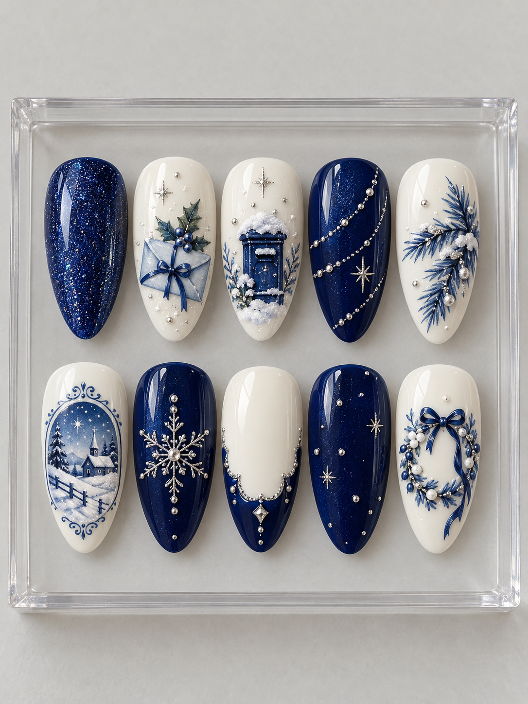 AI design mockup: Ten navy and ivory Christmas press-on nails with envelope, snowy mailbox, framed winter scene, blue wreath and silver-colour details.