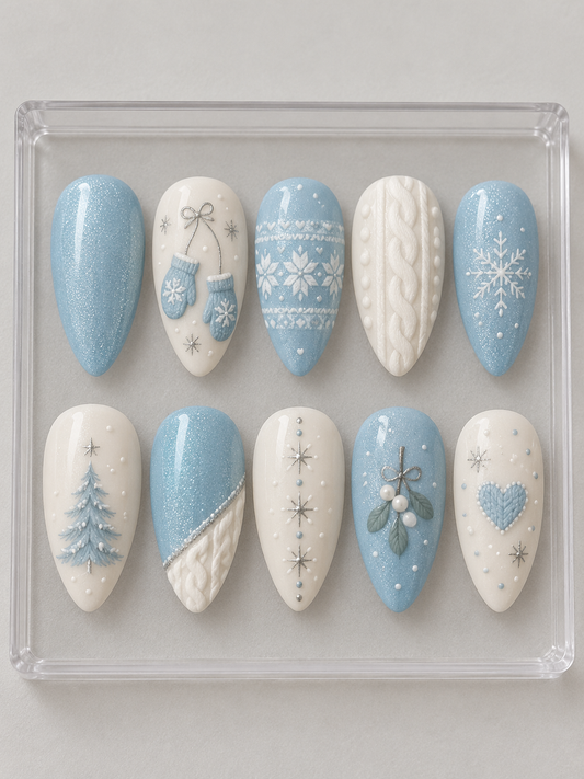 AI design mockup: Ten pale-blue and ivory Christmas press-on nails with mittens, cable-knit textures, fair-isle patterns, a tree and snowflakes.