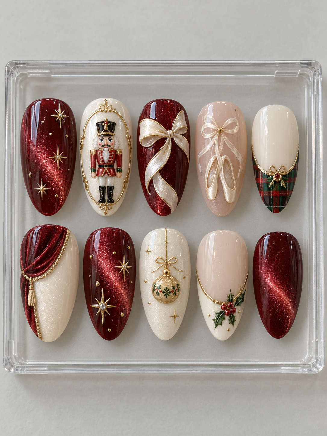 Ten burgundy and ivory Christmas press-on nails with nutcracker, ballet ribbons, gold stars, holly and tartan details.