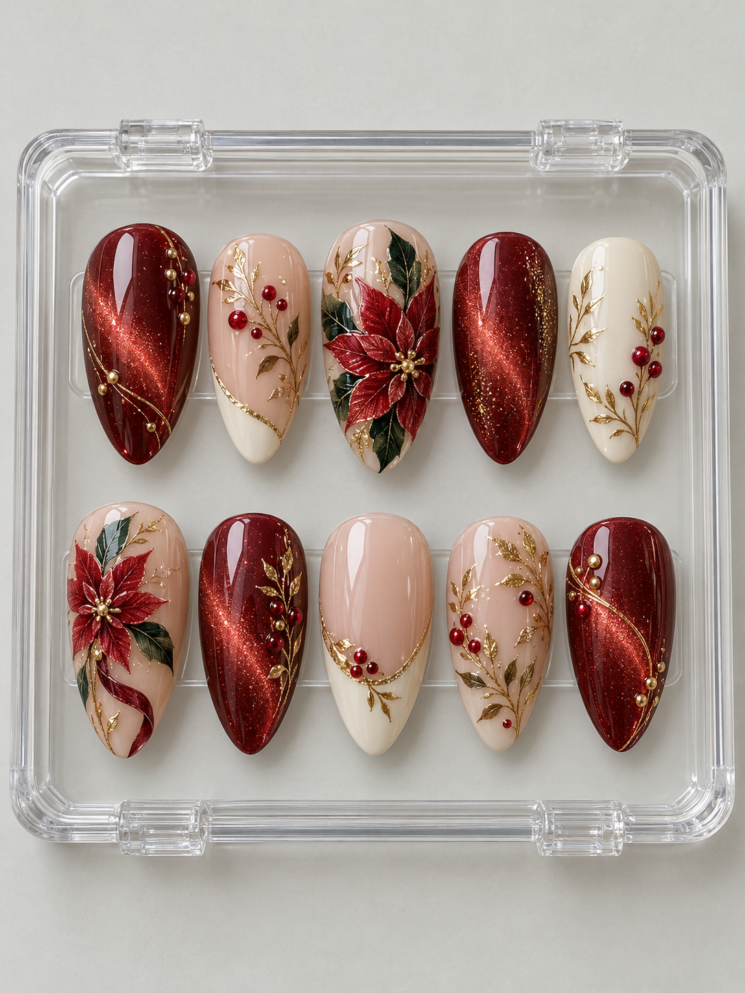 Ten ruby-red, nude and ivory Christmas press-on nails with poinsettia flowers, green leaves, red berries, gold-colour branches and French-style tips.