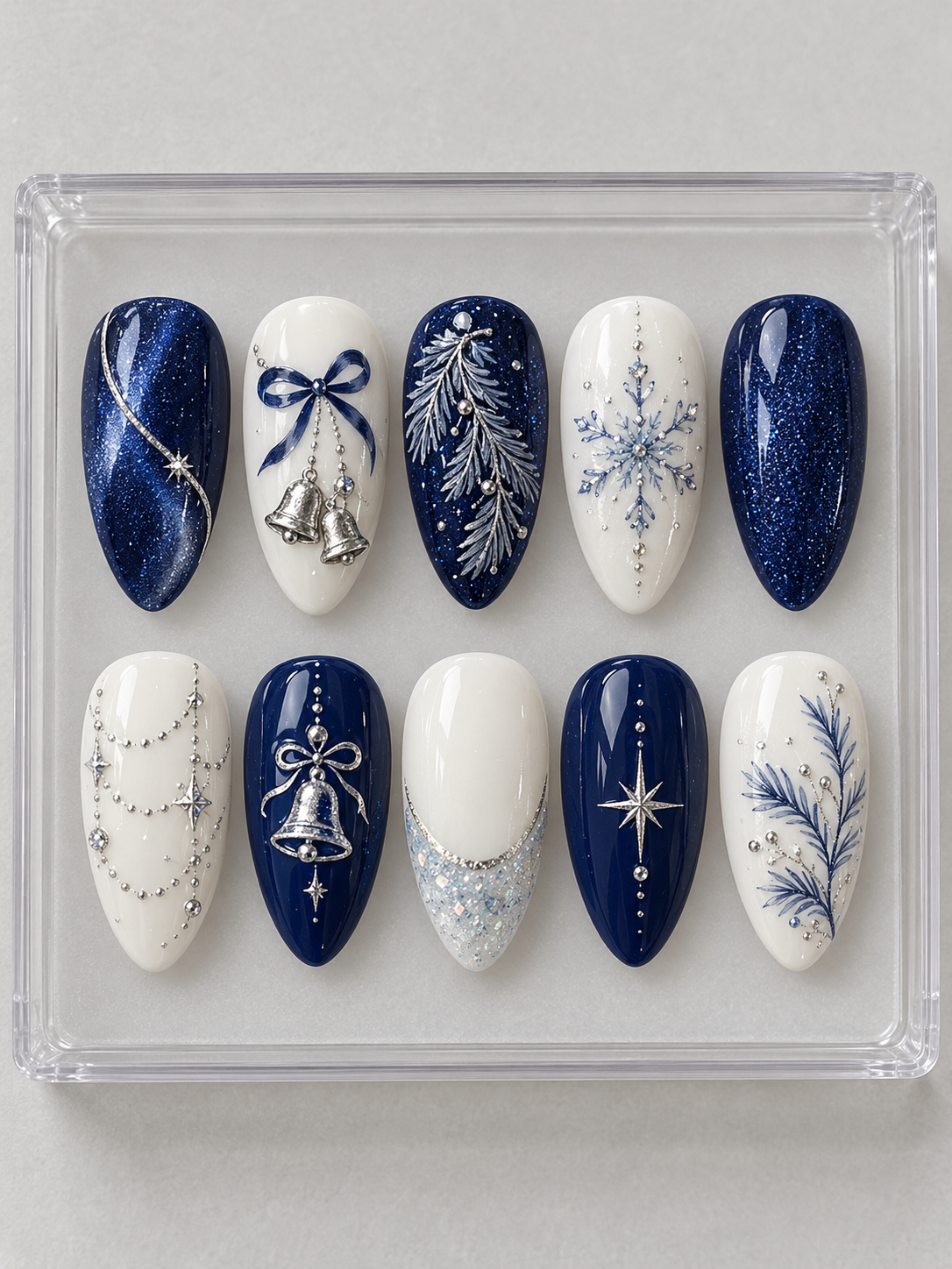 AI design mockup: Ten navy and ivory Christmas press-on nails with silver-colour bells, pine branches, snowflakes and draped accents.