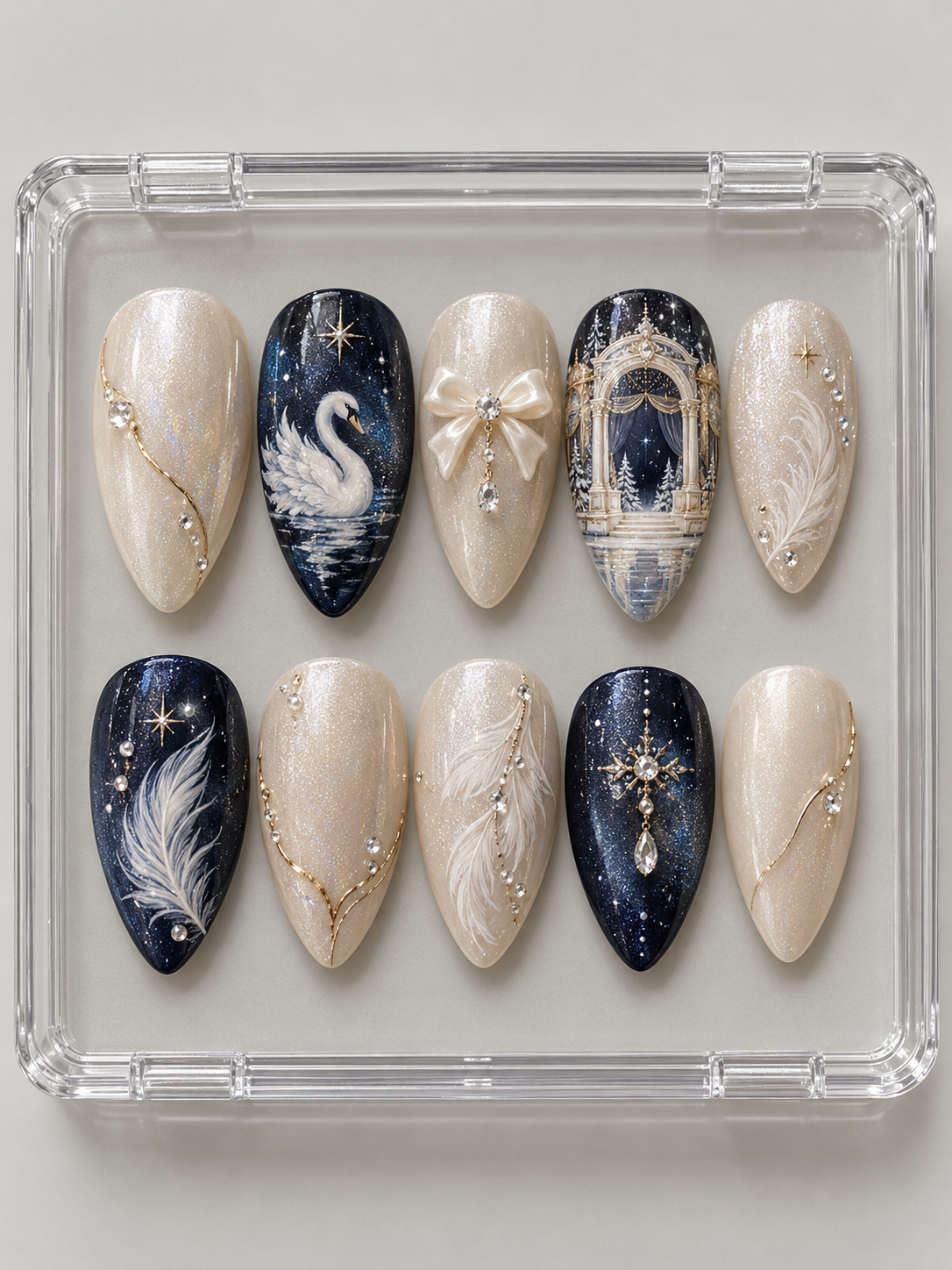 Ten navy and pearl-ivory Christmas press-on nails with white swan, theatre arch, feathers, ivory bow and crystal-look accents.